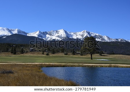 Golf course by snow covered mountains