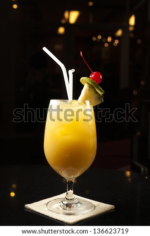Yellow cold cocktail with pineapple and cherry