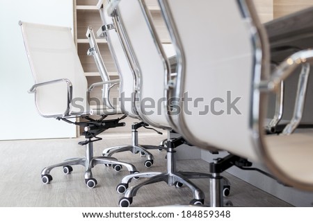 Set of empty office chairs next to long table in boardroom with low camera angle