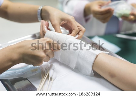 Wound dressing series : Closeup of hands of nurse dressing wound for patient\'s hand with burn injury