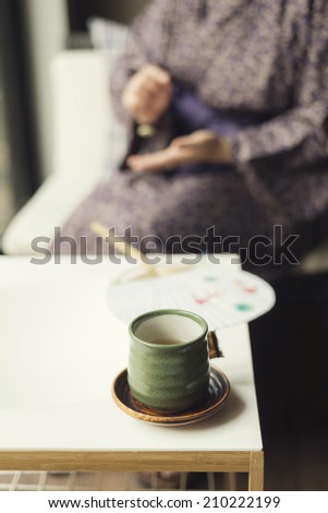 Onsen series : Teacup with woman wearing yukata in background