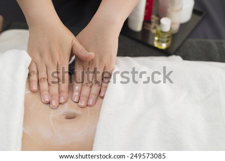 Therapist applying cream on woman's stomach