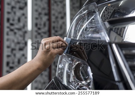 Car polishing series : Closeup of worker\'s hand using small sponge to waxing black car headlight