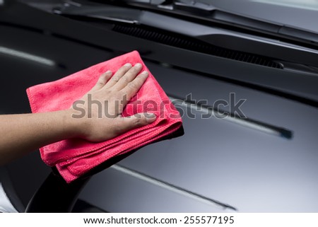 Car polishing series : Closeup of worker\'s hand using red towel cleaning black car hood