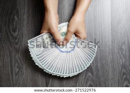 Female hand offering handful of hundred dollar banknotes