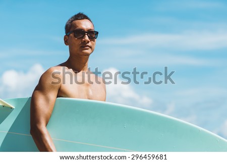 Asian man holding surf board looking at camera with color effect