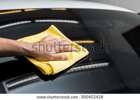 Car polishing series : Hand of worker using yellow towel wiping windshield