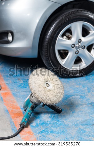Car polishing series : Electric Buffer Polisher on blue floor next to silver car