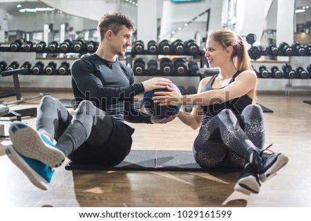 Sporty fitness couple doing abdominal exercises with medicine ball in the gym.