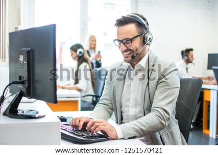 Smiling young male customer support executive in call centre