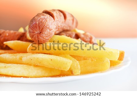 Fried sausage with french fries served on white plate and beauty background.
