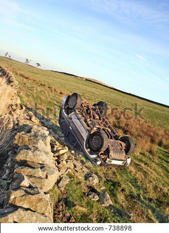 The morning after the night before. A four wheeled drive vehicle lies overturned after failing to take a bend and crashing through Stone wall, Police sign to side of veicle