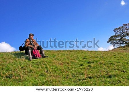 All Tucker out after a Hike in English Countryside man sits on Rock to enjoy the View