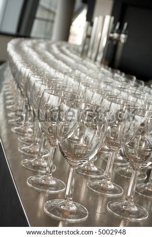 Get the round in, wine glasses all lined up and ready at wedding reception on modern chrome Bar with pumps in background