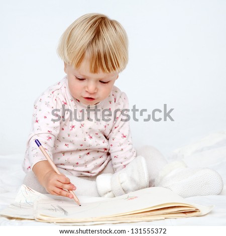 little girl sitting on bed drawing with pencil