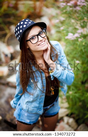 portrait of happy young female outdoors in casual wear smiling wearing glasses and hat view from above