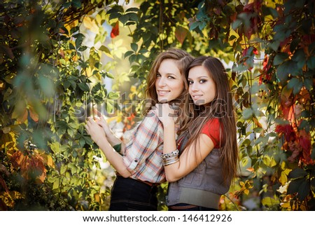 two girlfriends outdoors smiling looking at camera with wild grapes in background