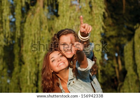 two teenage girls outdoors pointing in one direction