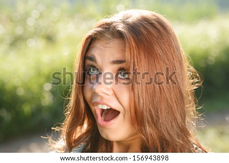 close-up portrait of surprised teenage girl outdoors with mouth opened looking away