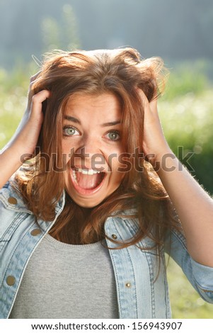 close-up portrait of shocked teenage girl outdoors with mouth opened looking at camera