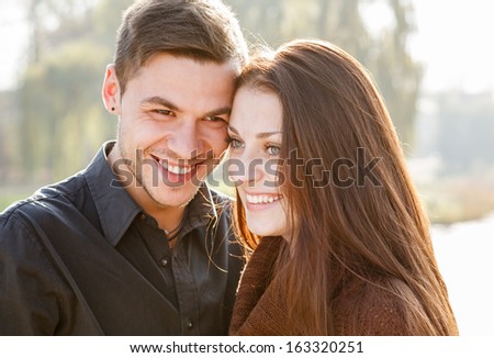 closeup of young couple outdoors laughing looking away heads together