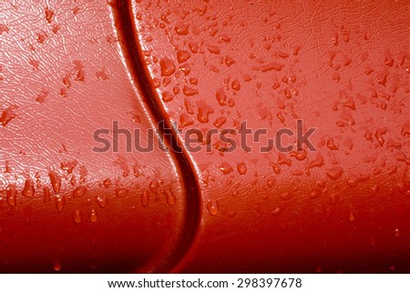Bright red metal roof surface with water drops.