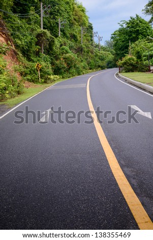 The road curves on the mountain. Line yellow and white road