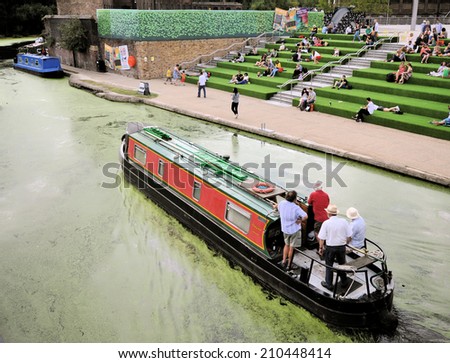 LONDON - AUGUST 9. A narrow boat on the Regent\'s Canal passing the Granary Square terraces, a leisure and cultural redevelopment on August 9, 2014 in the King\'s Cross area of London, UK.
