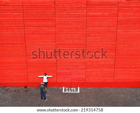 LONDON - JUNE 15. The red timber wall of the National Theatre\'s temporary venue is a popular backdrop for tourist photography on June 15, 2013, located at the South Bank, London, UK.