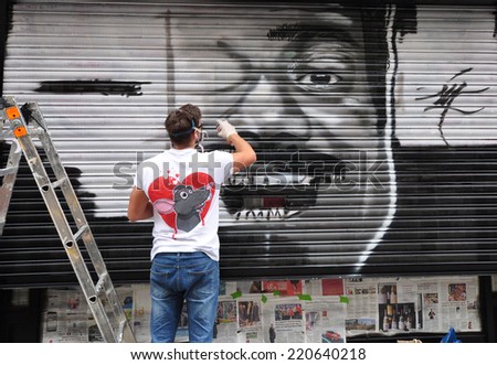 LONDON - SEPTEMBER 27. Street artist at work on shop security shutter on September 27, 2014 in Hanbury Street in the east end of London, UK.