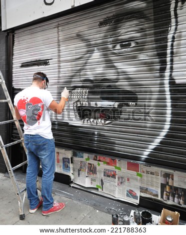 LONDON - SEPTEMBER 27. Street artist works on shopfront shutter on September 27, 2014 in Hanbury Street. east London, UK.