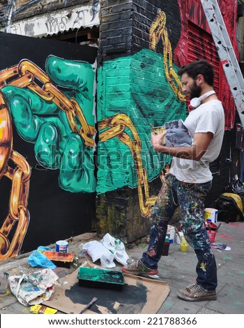 LONDON - SEPTEMBER 27. Street artist creates mural on derelict building site wall and hoarding on September 27, 2014 in Hanbury Street in east London, UK.