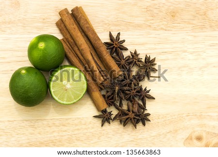 Anise and cinnamon spices arranged with lime fruits on the wooden chopping board.