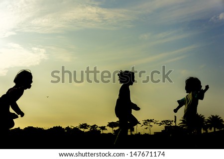 Silhouette group of happy children running and playing at park