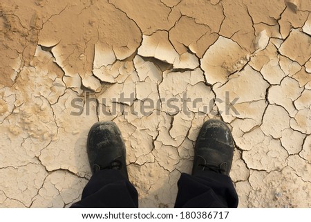 Feet of man standing on dry soil