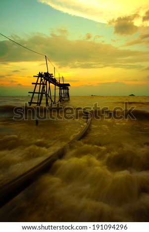 Silhouette wooden jetty with nice sunset background and warm white balance