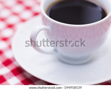 A cup of coffee on picnic blanket with shallow depth of field