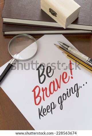 Blank paper with phrase Be Brave! Keep Going on desk.