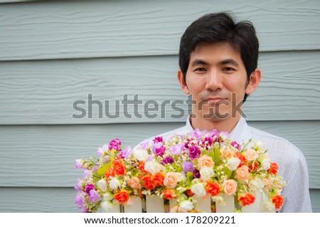 An asian man hold flower with wooden background