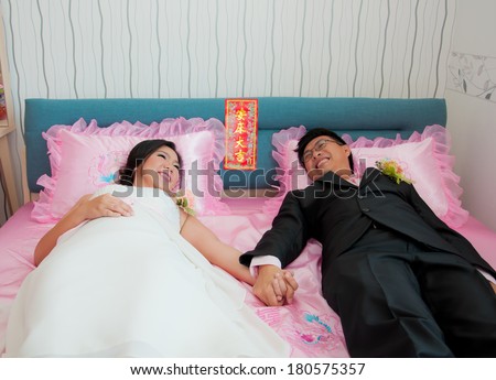 Bride and groom hold their hand and lay on the bed which beleive that they will live together till they die as Chinese Traditional