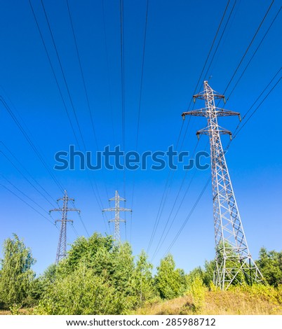 High-voltage power line with the poles, insulators and wires on a background of trees and sky