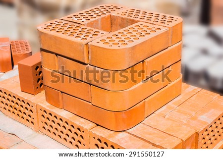 Several red perforated decorative brick with a rounded edge on pallet in depot closeup.