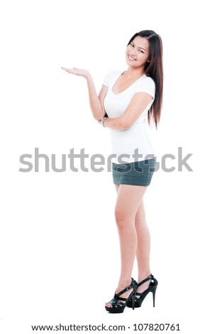 Full length portrait of a beautiful young Asian woman with hand outstretched, presenting things over white background