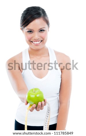 Portrait of happy young woman presenting apple and measuring tape over white background