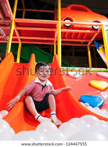 Happy young Asian boy playing in indoor playground