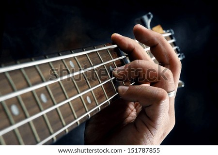Closeup of guitarist hand holding a chord on the guitar fretboard.