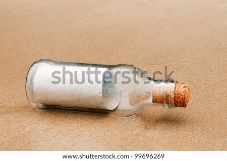 Blank brown paper in glass bottle lying on a beach.