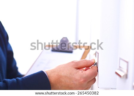Man\'s hand holding big folder from the shelves with office files