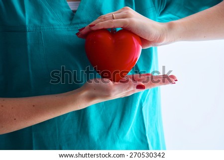 Female doctor with stethoscope holding heart over white background.