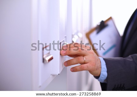 Man's hand holding big folder from the shelves with office files